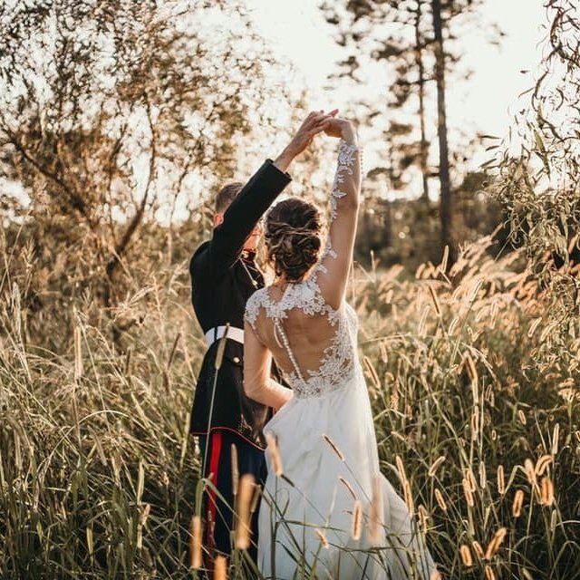 Bride and groom dancing in a field.