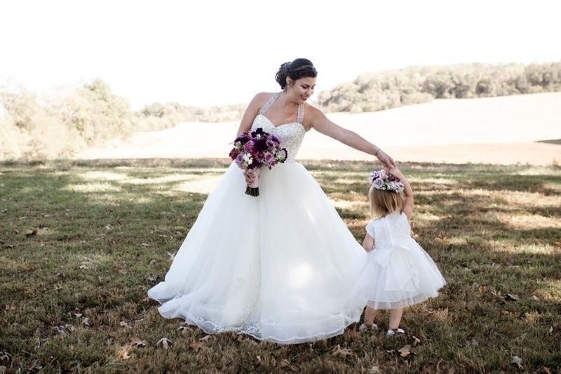 Bride in sweatheart neckline dress dancing with the flower girl.